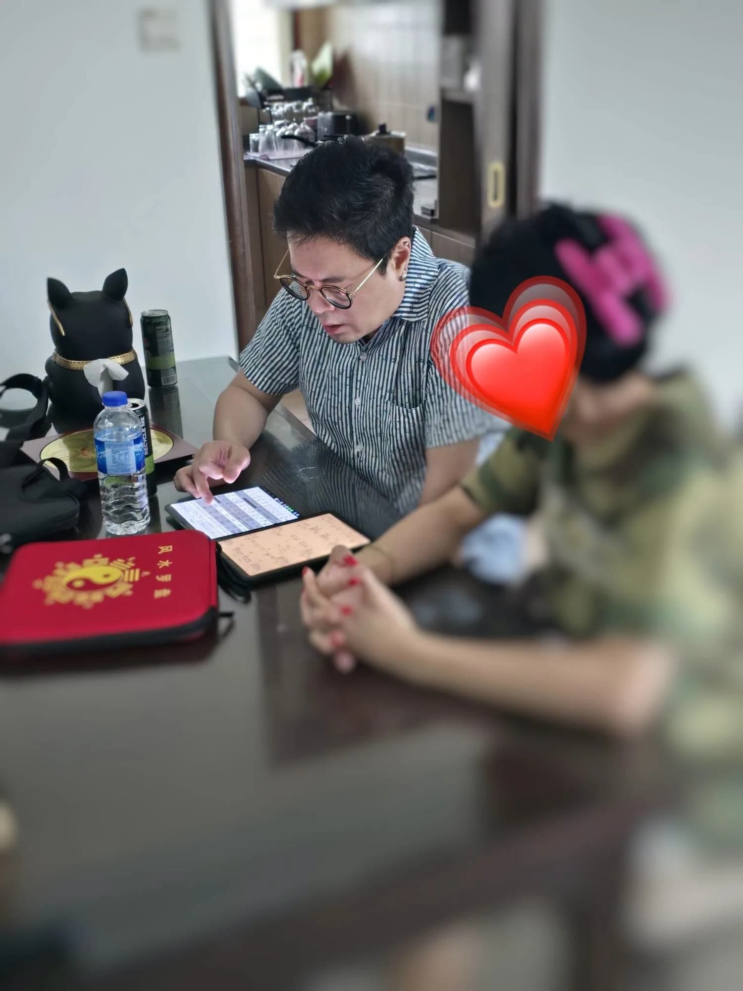 Master Jason reading a chart on a tablet for a client at his Feng Shui consultancy, City Gate