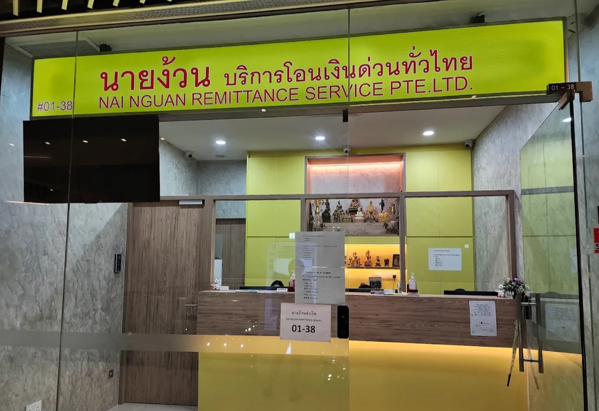 The Nai Nguan Remittance Service counter at City Gate #01-38, its yellow Thai-and-English signage above the glass front