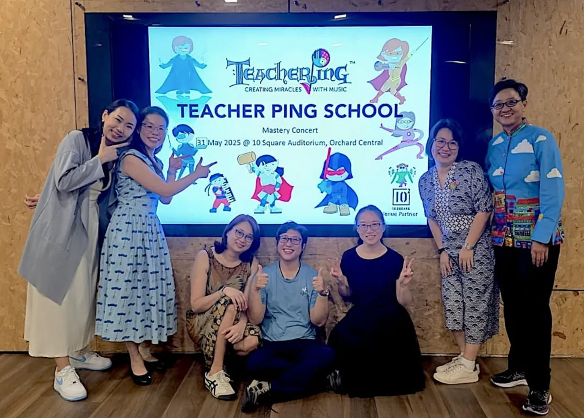 The Teacher Ping School of Music team at their Mastery Concert, in front of the school's branded screen