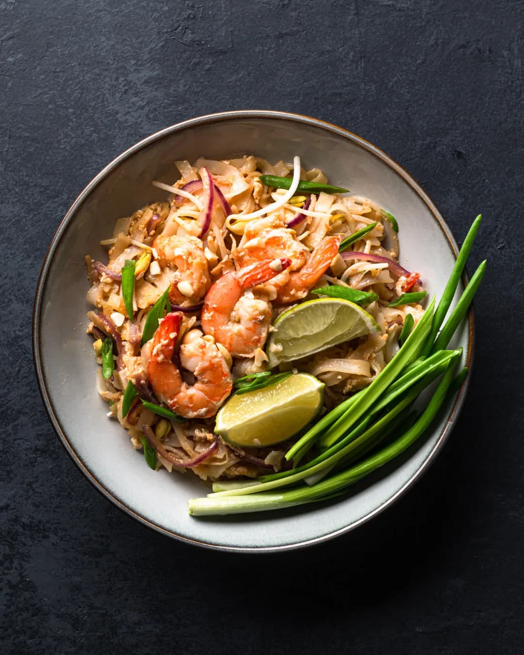 A bowl of prawn pad thai with lime, spring onion and red onion — Thai flavours at City Gate