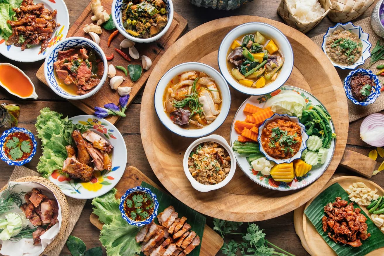 A Thai feast of curries, grilled meats and fresh herbs spread across a wooden table — the Golden Mile flavours at City Gate