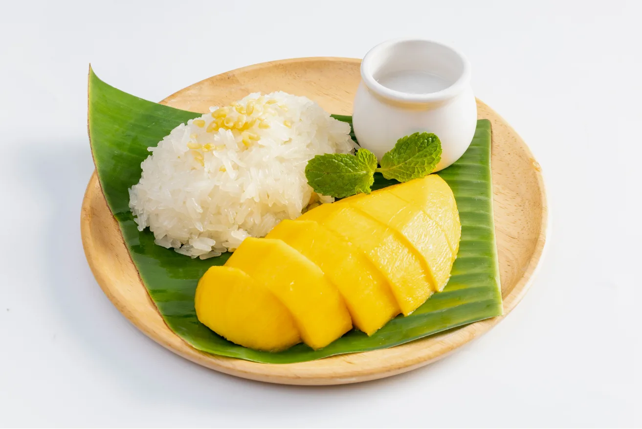 Mango sticky rice with coconut cream and mint on a banana leaf — a Thai classic at City Gate