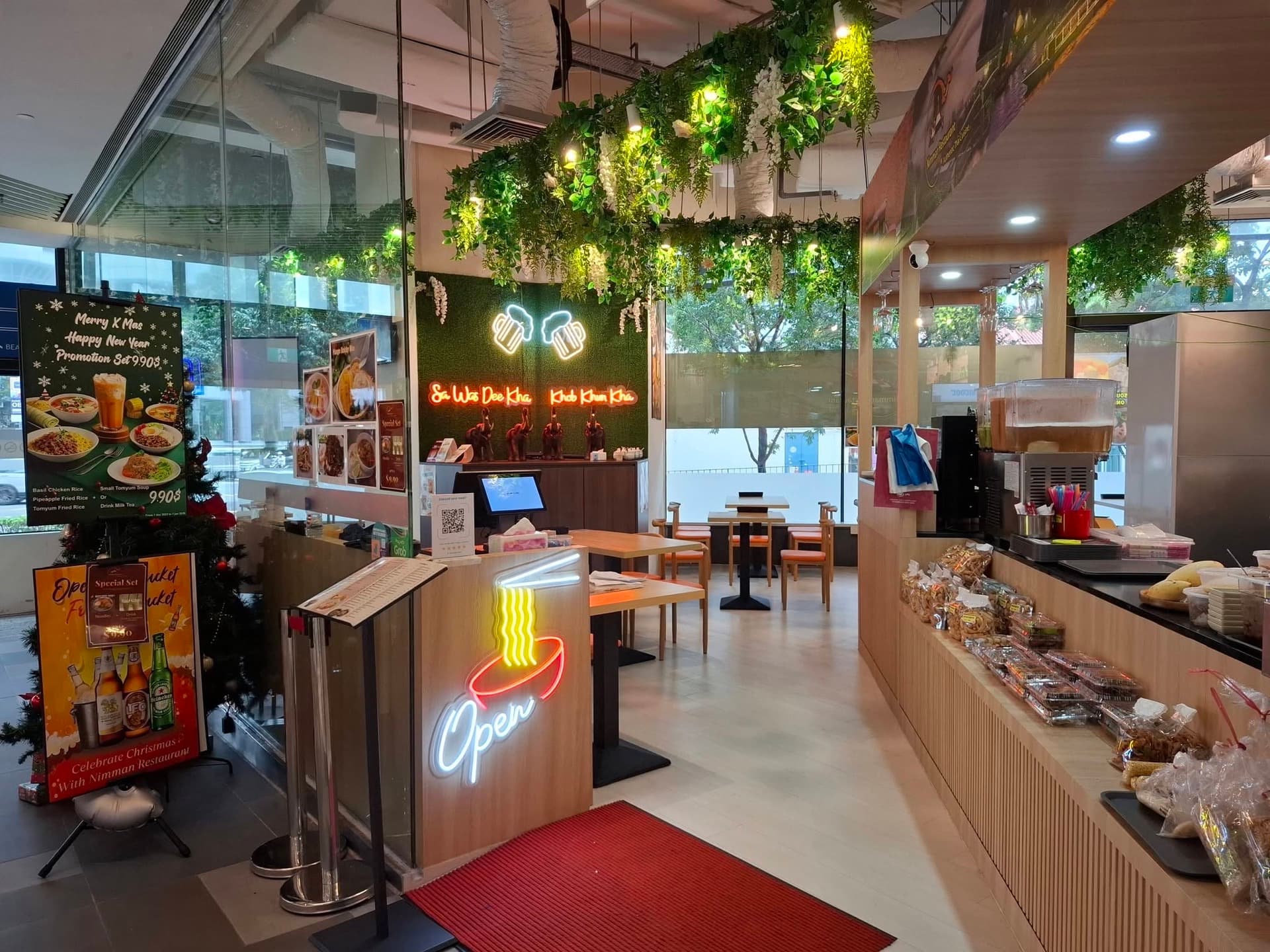 The Nimman Restaurant storefront at City Gate — neon open sign, greenery and dining tables
