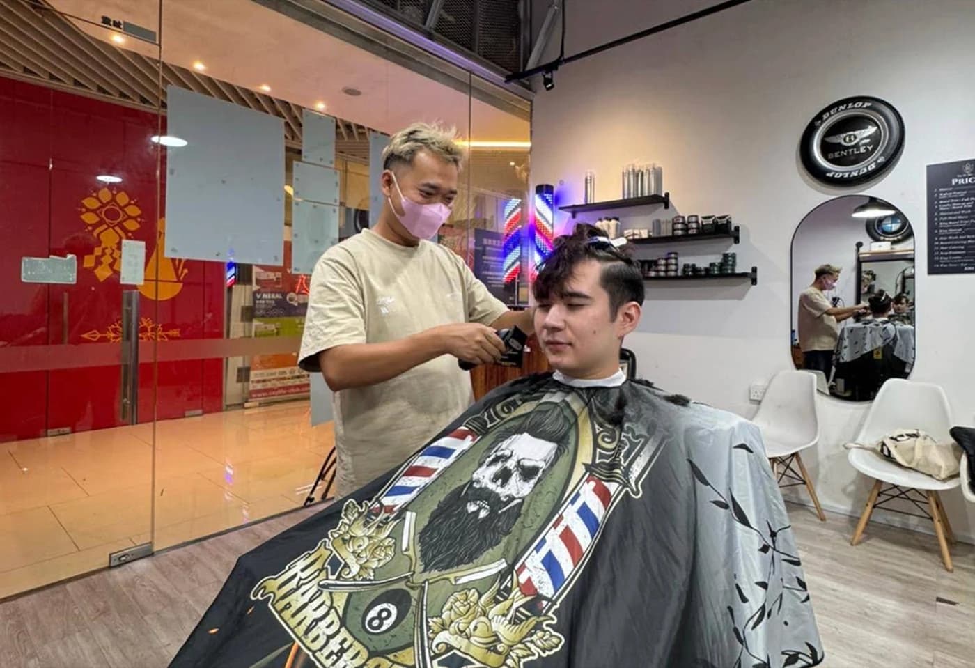 A barber giving a fresh cut at King of Shave, City Gate — barber pole, price board and mirror stations
