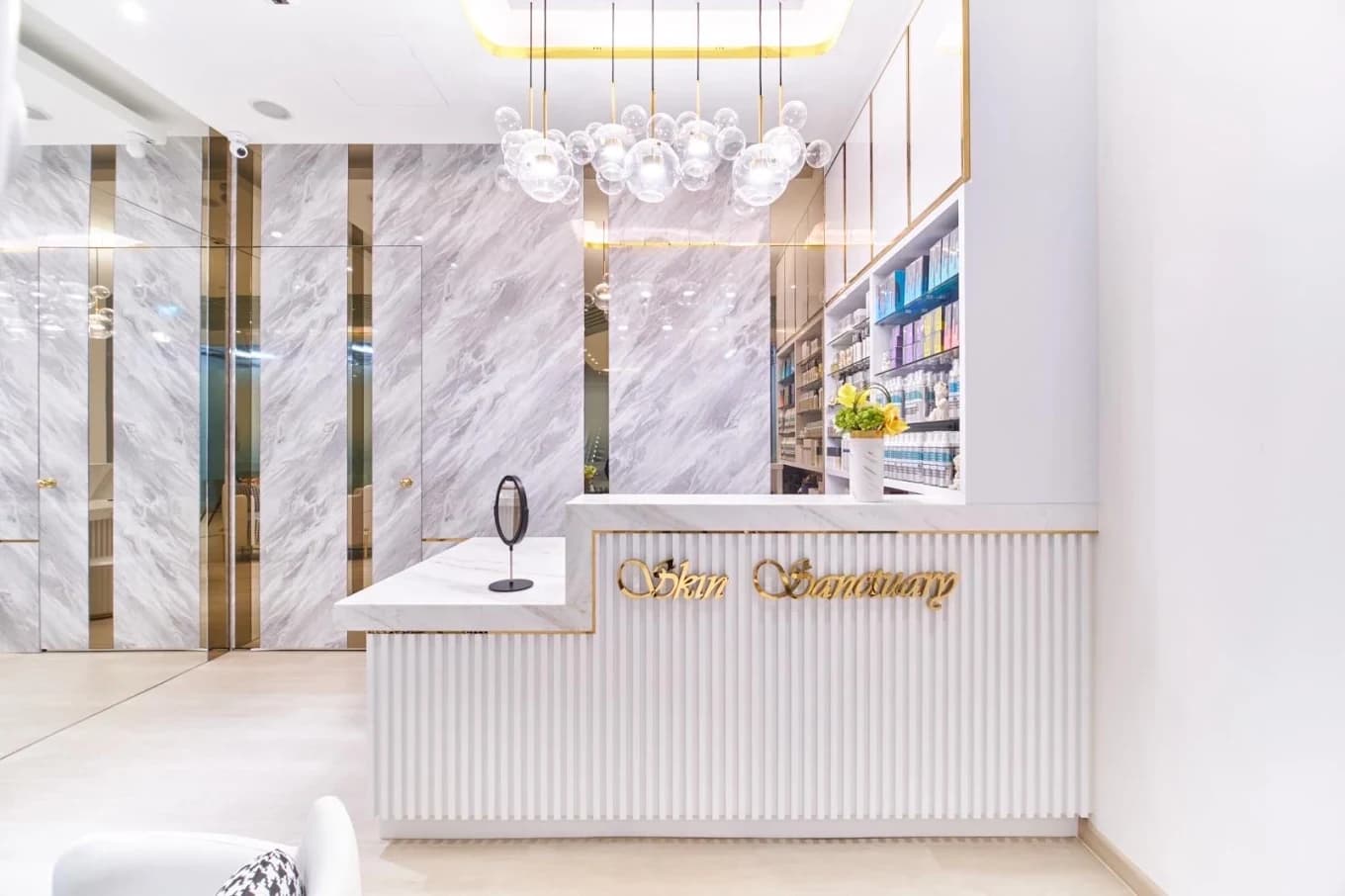 The Skin Sanctuary reception at City Gate, a marble and gold counter with the shop name in gold script under a bubble chandelier